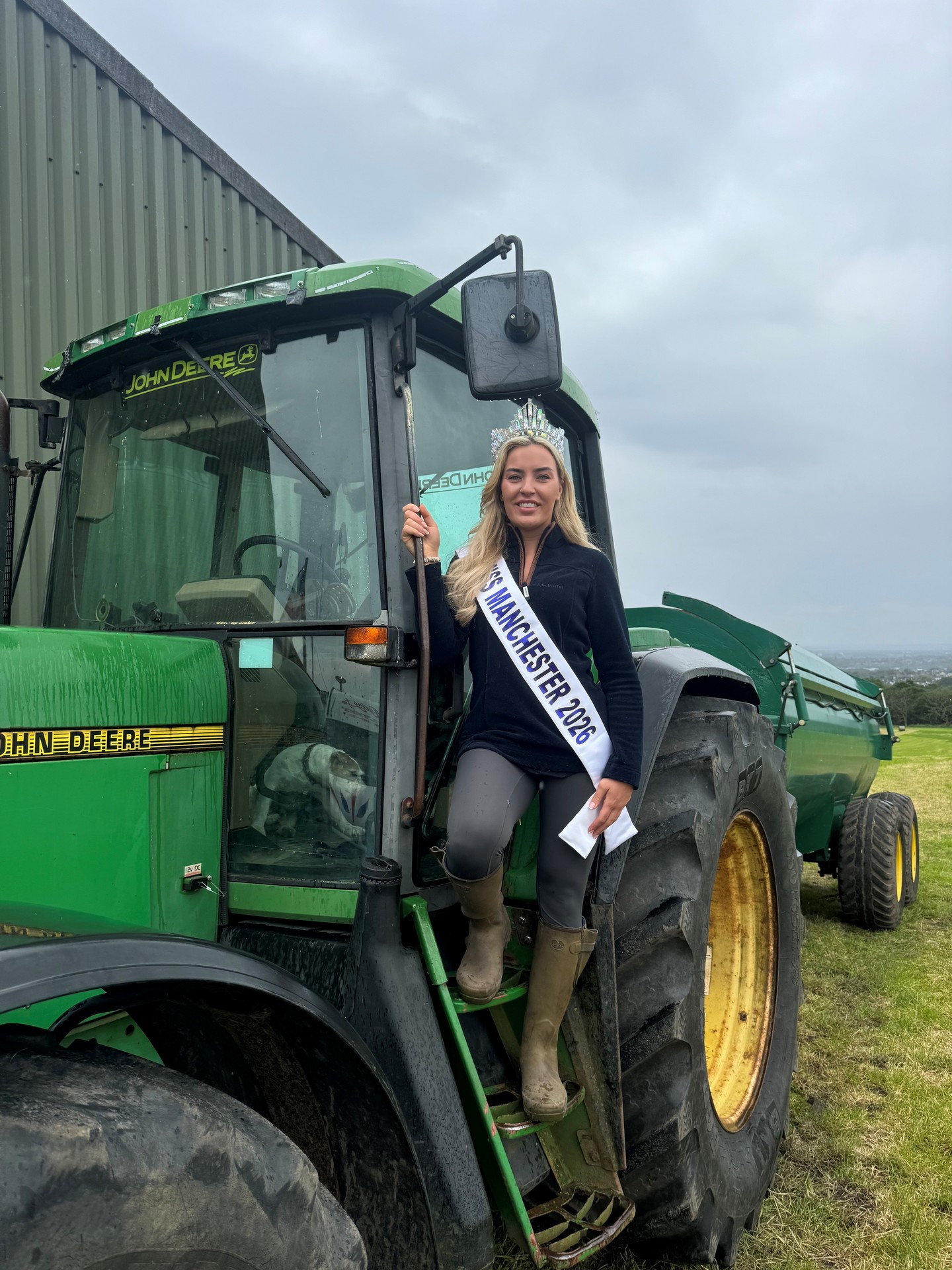 Clare Hopwood in her crown, Miss Manchester sash and wellies beside a tractor